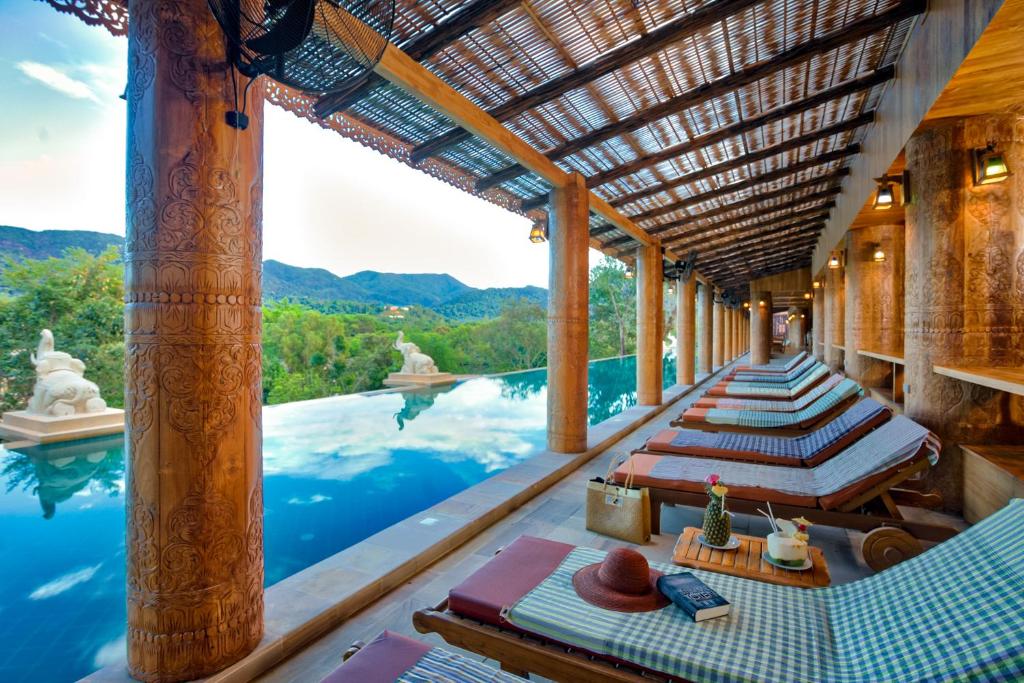 Relaksācijas zona ar saulessargiem un baseinu, kas piedāvā skatu uz kalniem. Interjers ir veidots ar koka elementiem un siltām krāsām, radot mierīgu atmosfēru.