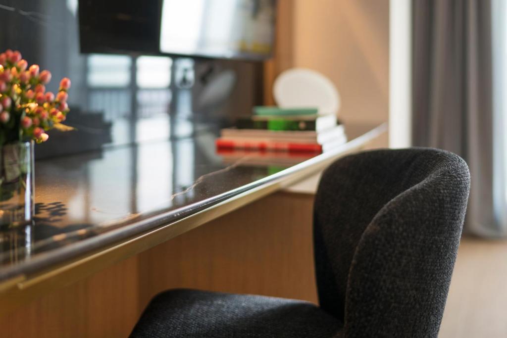 Mūsdienīgs rakstāmgalds ar melnu krēslu, ziedu kompozīcija un grāmatas, radot elegantu un funkcionālu darba vidi.