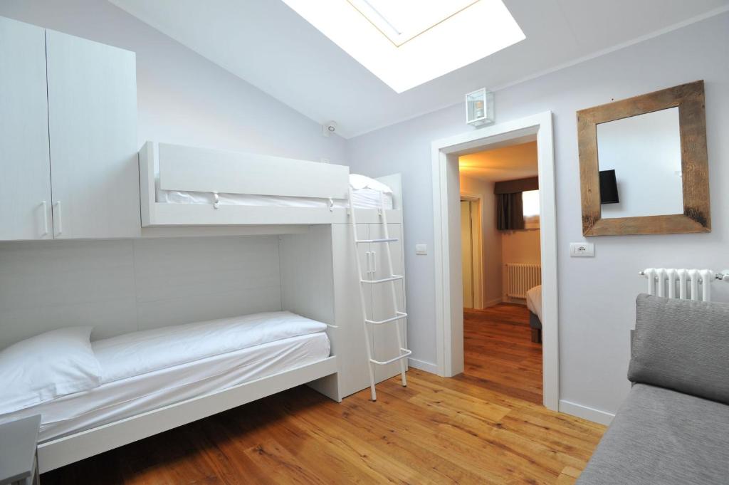 Gaišs un moderns guļamistabas interjers ar diviem gultas līmeņiem, koka grīdu un logu ar jumta lūku. Telpā ir arī dīvāns un spogulis, kas rada mājīgu atmosfēru.