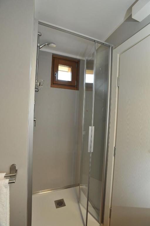 Mūsdienīga dušas kabīne ar stikla durvīm un logu, kas ļauj ieplūst dabīgajai gaismai. Telpa ir gaiša un funkcionāla.