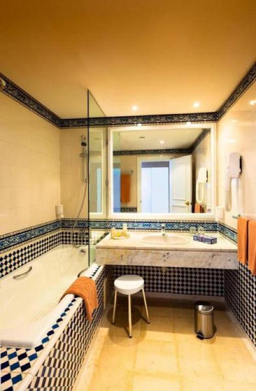 Mūsdienīga vannas istaba ar elegantu melnbalto flīžu dizainu, vannu un izsmalcinātu izskatu. Svaigs un gaišs interjers ar lielu spoguli un praktiskām mēbelēm.