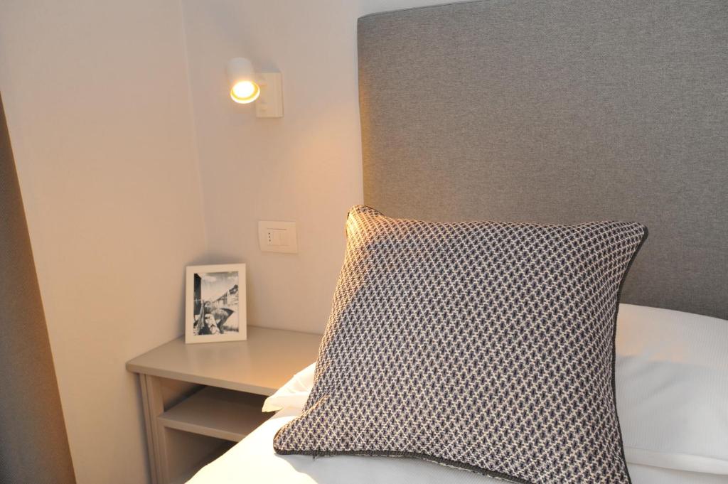 Mūsdienīgs gultas stūris ar dekoratīvo spilvenu, blakus atrodas galdiņš ar rāmīti un gaismekli.