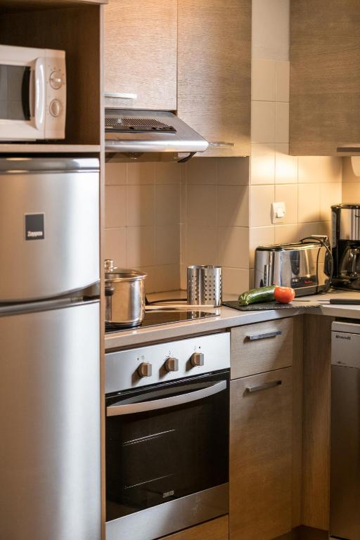 Mūsdienīga virtuve ar sudraba krāsas ledusskapi, plīti un dažādiem virtuves piederumiem, tostarp dārzeņiem uz galda.