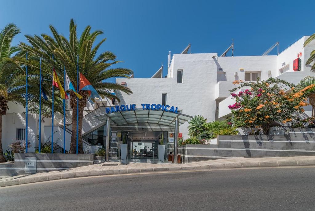 Ieeja viesnīcā Parque Tropical ar palmām un ziediem ap to.