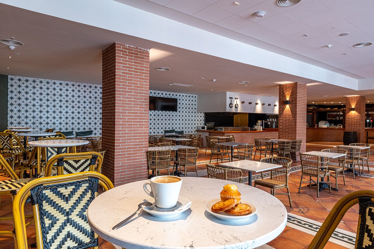 Kafijas tase un smalkmaizītes uz galdiņa Estival Park Marena kafejnīcā