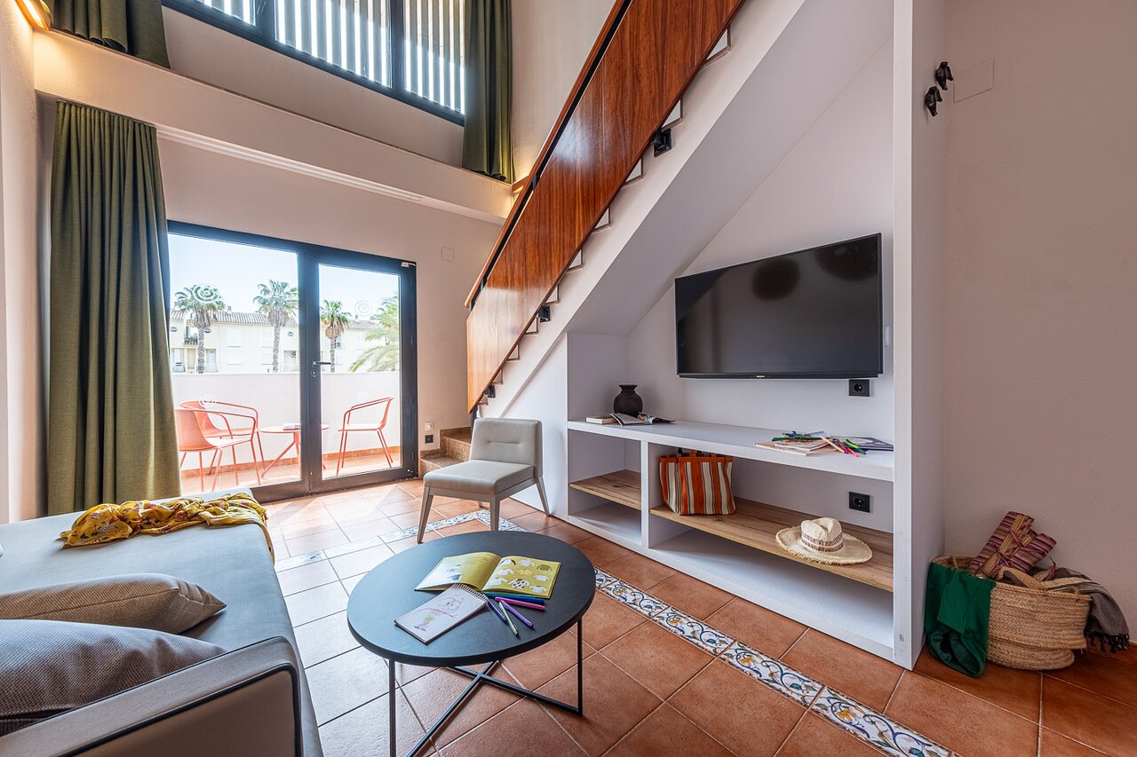 Estival Park Marena divlīmeņu ģimenes numurs ar viesistabas zonu un koka kāpnēm.