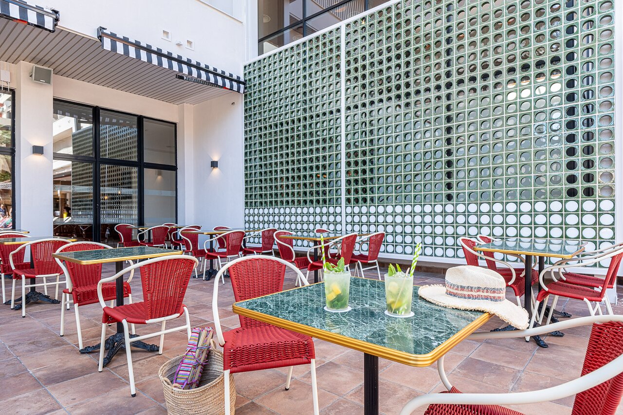 Estival Park Marena āra terase ar atspirdzinošiem kokteiļiem, sarkanu pīto krēslu atpūtas zonu un vasarīgu atmosfēru.