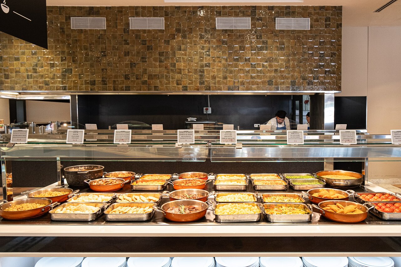 Estival Park Marena restorāna bufetes galds ar daudzveidīgu karsto ēdienu izvēli un pavāru fonā.