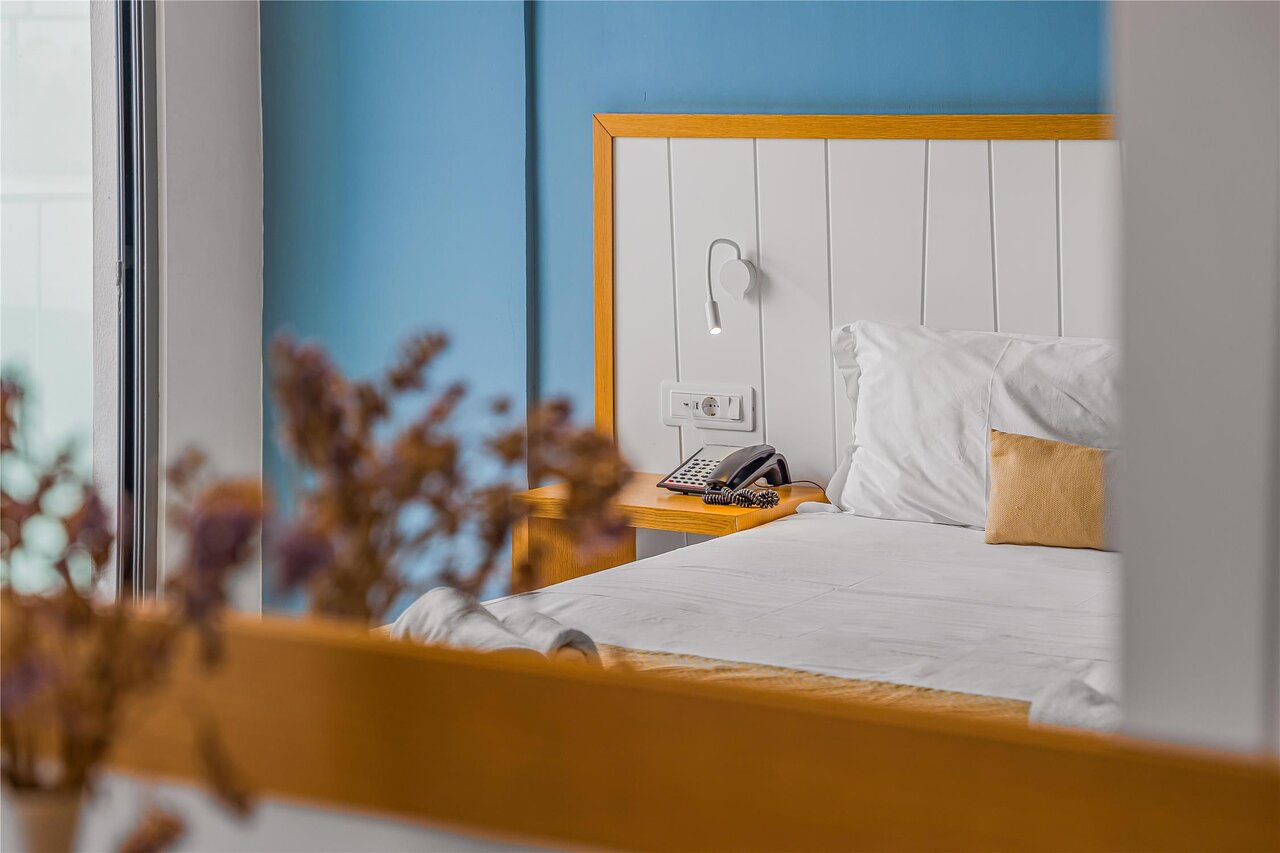 Mājīgs Panorama Village Hotel numurs ar ērtu gultu, telefonu un modernu dizainu.