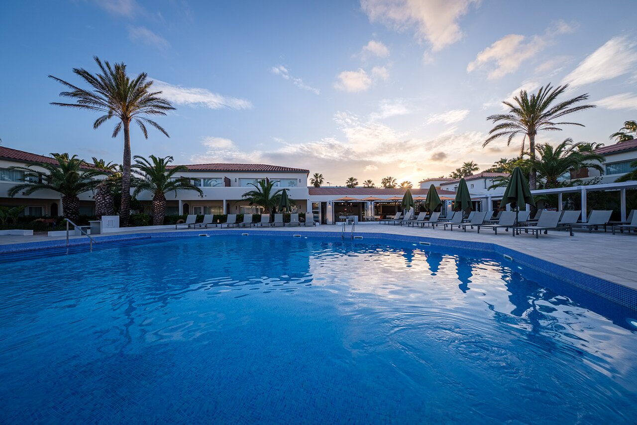 Oassium Hotel - Adults Only āra baseins ar atpūtas krēsliem mierīgā vakara noskaņā.