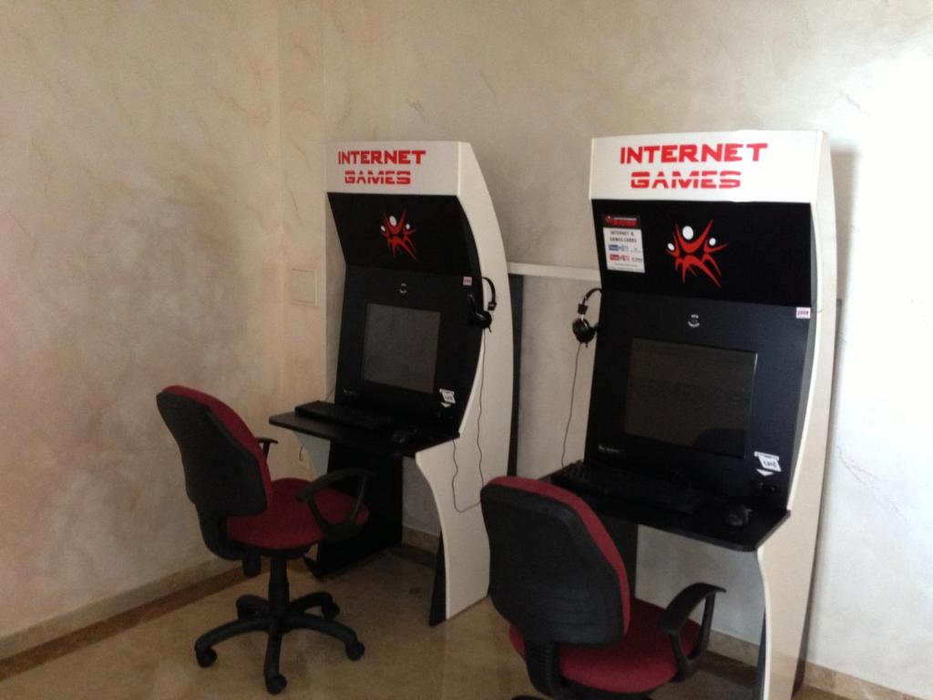 Datoru stacija ar diviem spēļu termināļiem, katrā ir monitors, tastatūra un austiņas. Telpa ir gaiša un vienkārša.