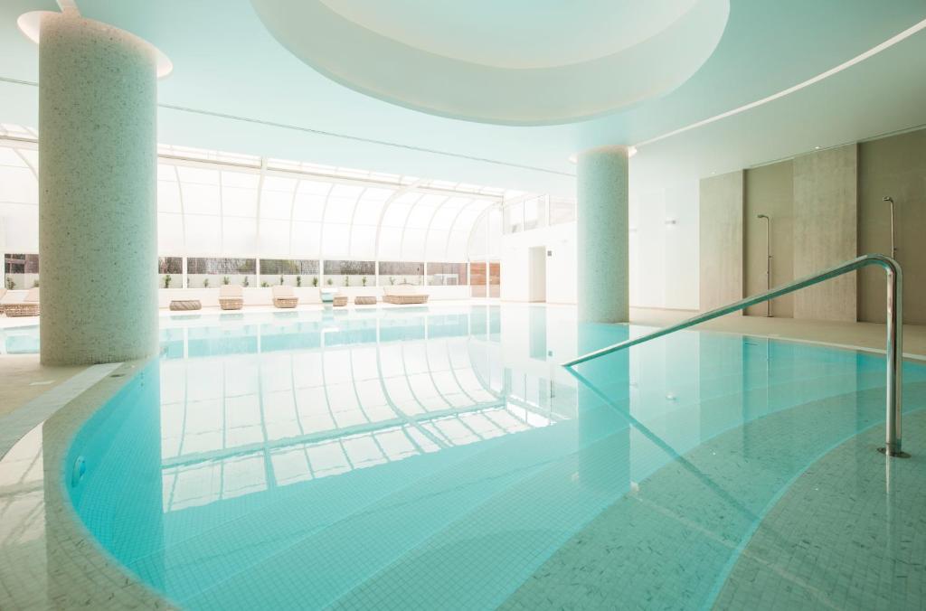 Mūsdienīgs iekštelpu peldbaseins ar stikla jumtu, apgaismots ar dabiskiem gaismas stariem. Baseinā atspoguļojas apkārtējā vide, radot mierīgu un relaksējošu atmosfēru.