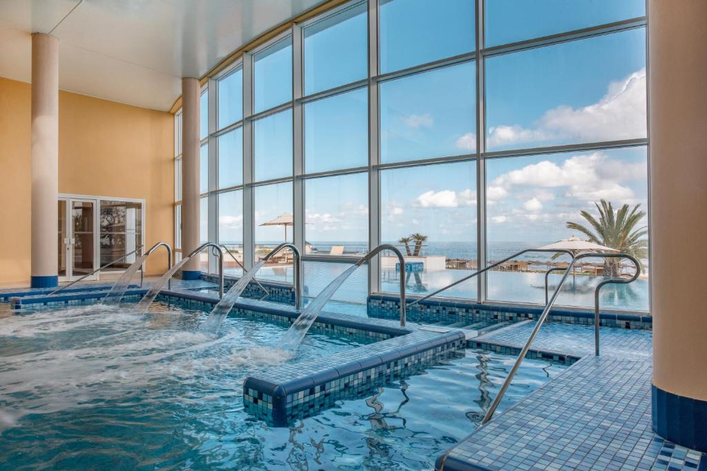 Luksusa spa telpa ar lieliem logiem, caur kuriem redzama jūra un palmas. Ūdens strūklas un relaksējoša atmosfēra.