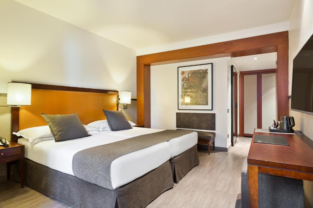 Moderns viesnīcas numurs ar divām gultām, elegantu interjeru un mākslas darbu uz sienas. Numurā iekļautas ērtības, piemēram, televizors un kafijas automāts.