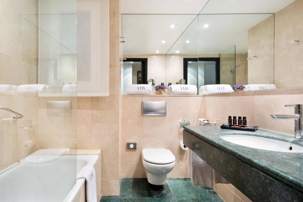 Moderns vannas istabas interjers ar marmora sienām, vannu un elegantu izlietni. Rūpīgi sakārtoti tualetes piederumi un dvieļi.