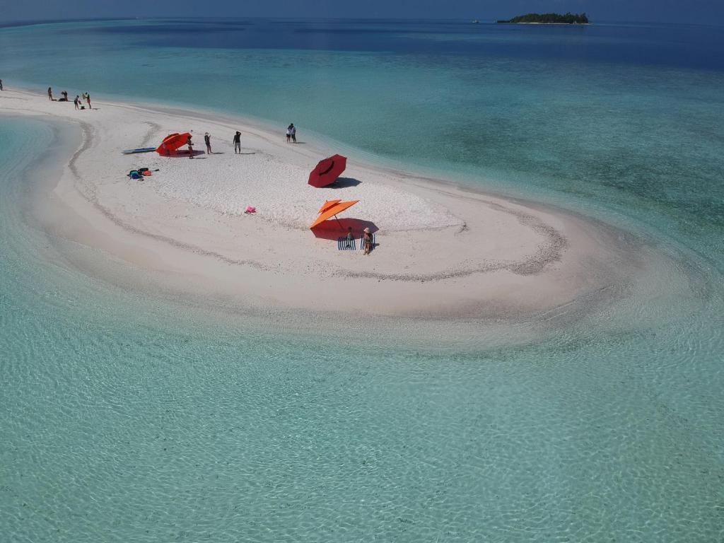 Klejojoša pludmale ar balto smiltīm un skaidru ūdeni, kur cilvēki atpūšas zem saulessargiem. Šī idilliskā aina atspoguļo tropisko paradīzi.
