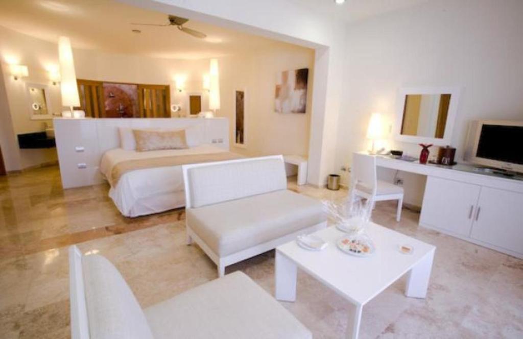 Luksusa viesnīcas numurs ar modernu interjeru, kurā ir komfortabla gulta, atpūtas zona un televizors. Telpa ir gaiša un plaša, radot relaksējošu atmosfēru.