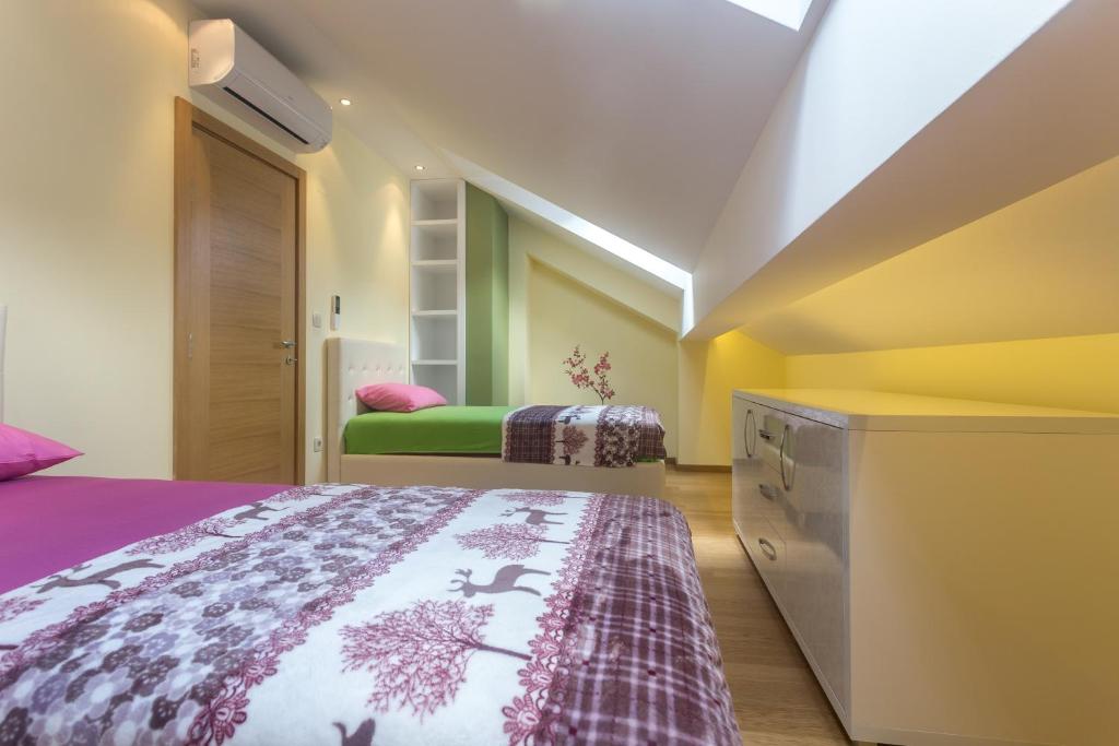 Gaiša un moderna guļamistaba ar divām gultām, kuras rotā krāsaini gultas veļas komplekti. Telpā ir gaismas elementi un skapītis, kas piešķir mājīgu atmosfēru.