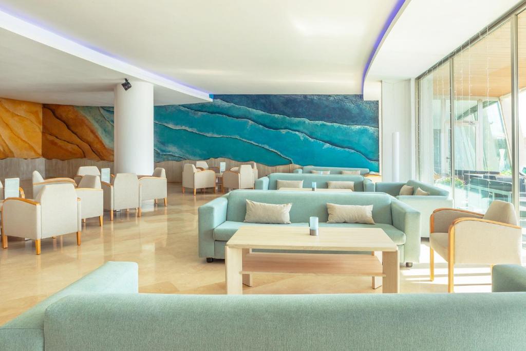 Mūsdienīgs un elegants interjers ar gaisīgām, gaišām krāsām un modernu mākslu, kas attēlo jūras viļņus. Komfortabli dīvāni un galds veido relaksējošu atmosfēru.