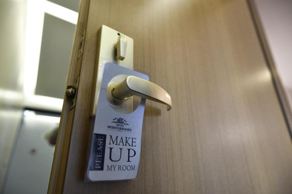Durvju rokturis ar zīmi "Lūdzu, sakopiet manu istabu" viesnīcā Mediterranée.