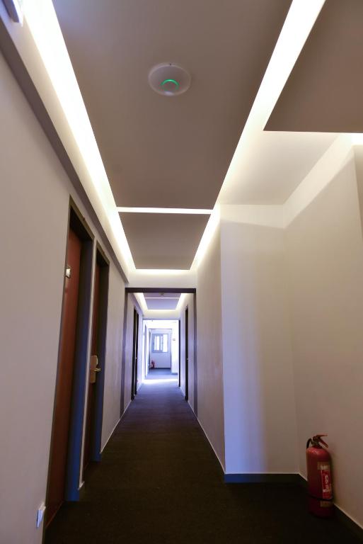 Moderns viesnīcas koridors ar apgaismojumu pie griestiem un ugunsdzēsības aparātu.