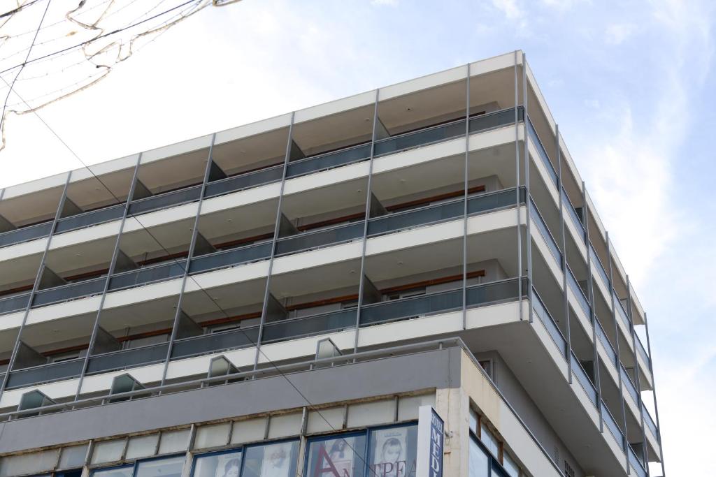 Mūsdienīga daudzdzīvokļu ēka ar balkoniem un skaidru debesu fona.