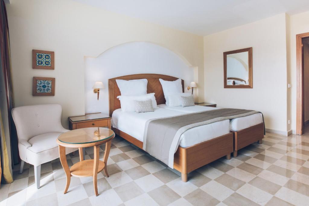 Mūsdienīga viesnīcas numura interjers ar divguļamo gultu, ērtu krēslu un mazu galdu. Svaiga, gaiša atmosfēra ar elegantām dekorācijām.