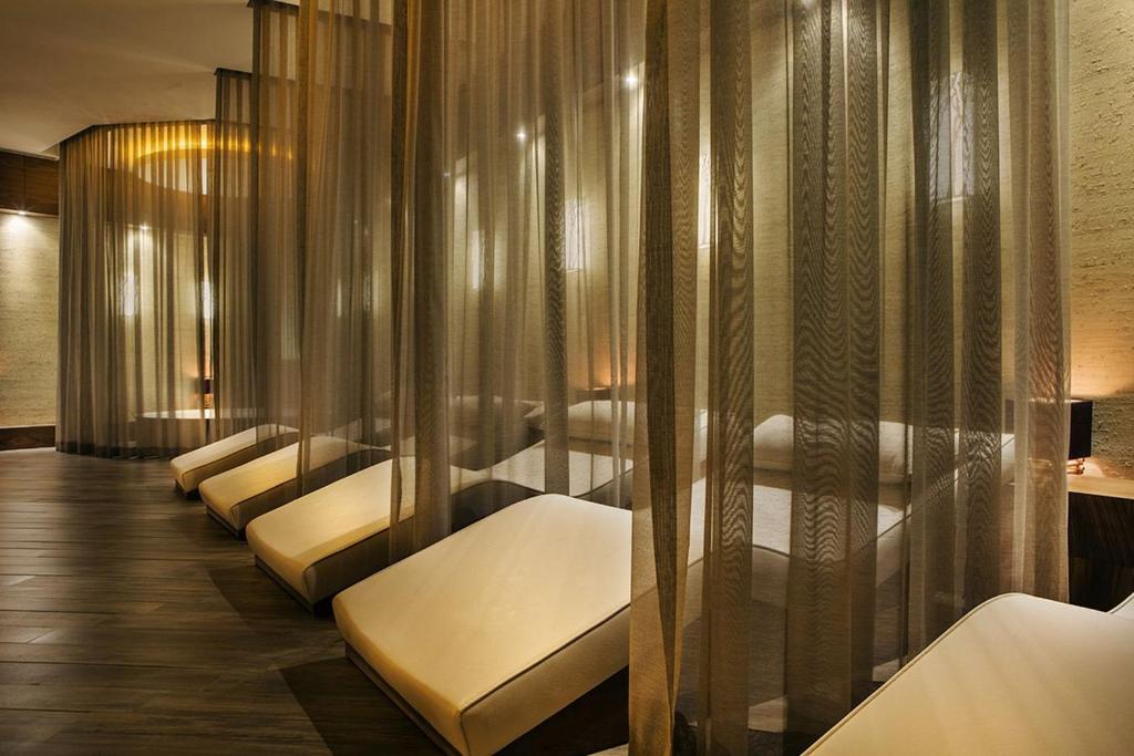 Mūsdienīgs spa telpas interjers ar relaksācijas krēsliem, kas nodalīti ar caurspīdīgiem aizkariem. Siltas gaismas un koka grīdas radītas mierīgas atmosfēras sajūtu.