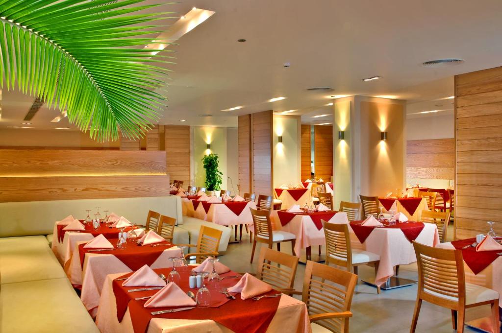 Moderns restorāns ar elegantiem galdiem un sarkanām galdautām, greznu apgaismojumu un zaļām augiem. Ideāli piemērots romantiskām vakariņām vai svinībām.