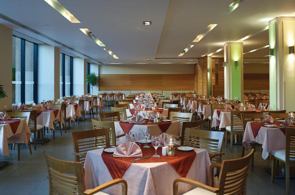 Lieliska restorāna iekārtojuma skats ar eleganti klātiem galdiem un mūsdienīgu interjeru, radot patīkamu atmosfēru.