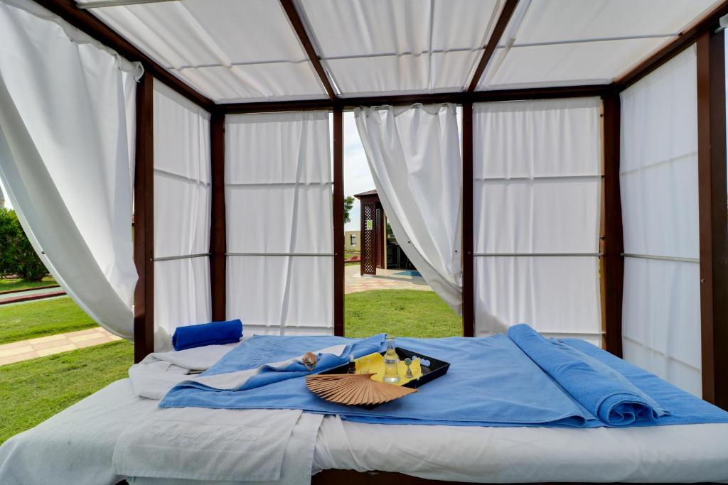 Spa telts ar masāžas galdu, uz kura izvietoti dvieļi un aromātiskas sveces, apkārt skaista zaļā vide.