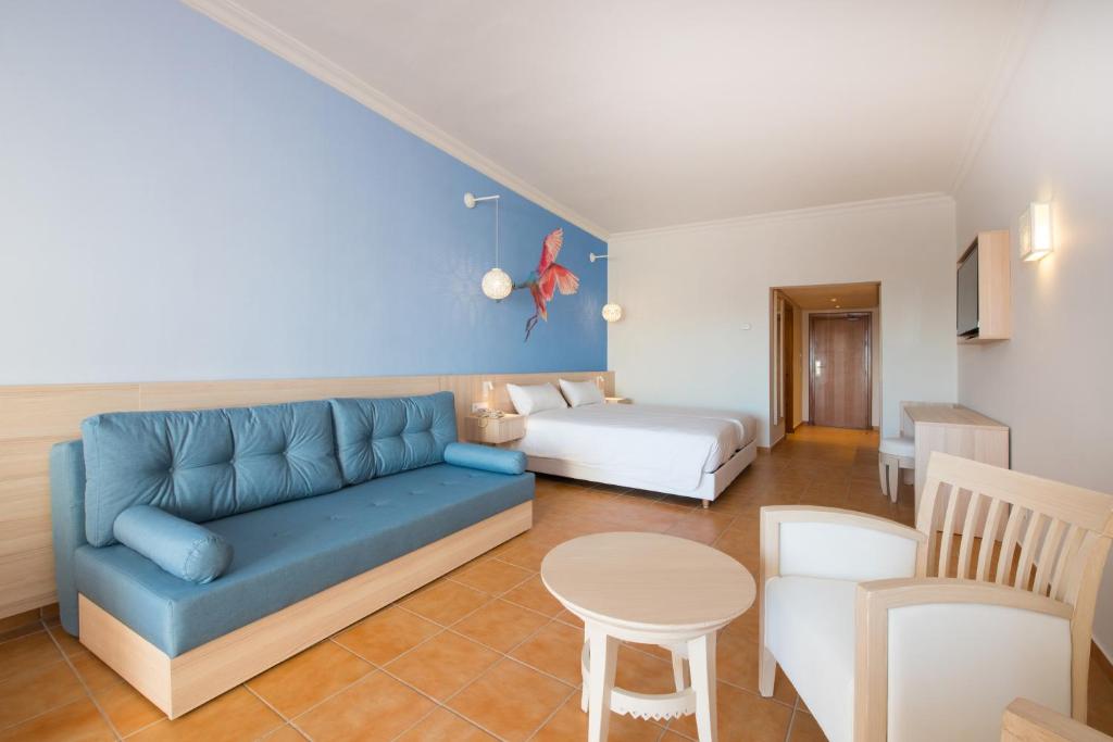 Mūsdienīgs viesnīcas numurs ar gaišām krāsām, ērtiem mēbeļu komplektiem un māksliniecisku sienas gleznojumu. Numurā ir dīvāns, gulta un galdiņš.