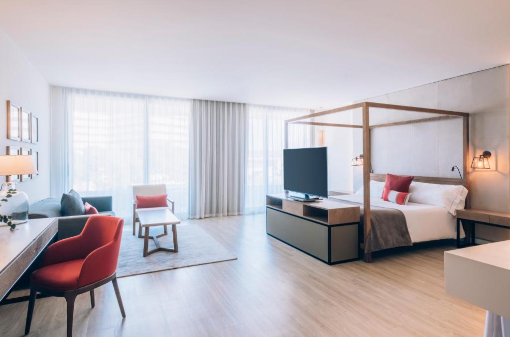Mūsdienīgs viesnīcas numurs ar plašu guļamistabu, komfortablu dīvānu un elegantu interjeru, kas nodrošina relaksējošu atmosfēru. Lieli logi ļauj ieplūst dabīgā gaismā, radot siltu un patīkamu vidi.