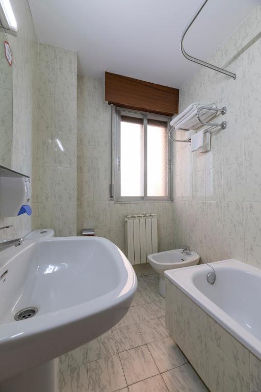 Mūsdienīgs vannas istabas interjers ar izlietni, bidē un vannu, kas apgaismota ar dabiskiem gaismas avotiem. Eleganta un funkcionāla dizaina akcenti.