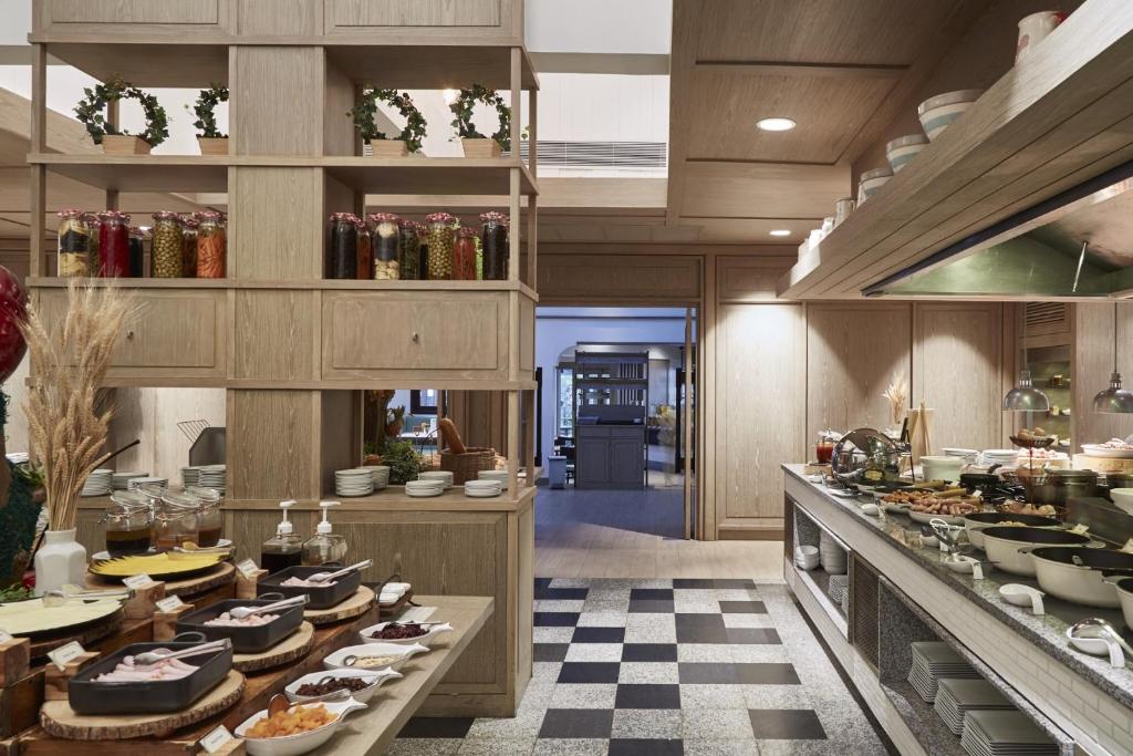 Mūsdienīga restorāna iekšiene ar bufetes galdu, dekoratīvām burkām un plašu izvēli ēdienu. Gaisīga un silta atmosfēra, kas aicina apmeklētājus.