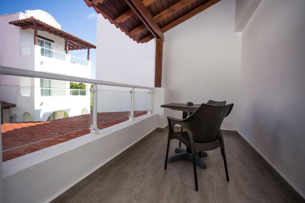 Balkons ar galdu un krēslu, ar skatu uz blakus esošajiem ēkām un sarkano jumtu. Moderns dizains ar koka detaļām un dabīgu apgaismojumu.