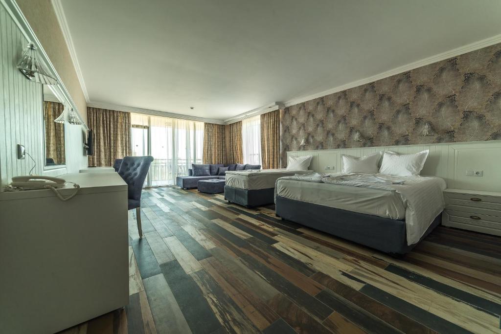 Moderns viesnīcas numurs ar divām gultām, dīvānu un plašām logu daļām, kas nodrošina dabisko apgaismojumu. Grīda izgatavota no dažādu krāsu koka dēļiem, radot siltu atmosfēru.