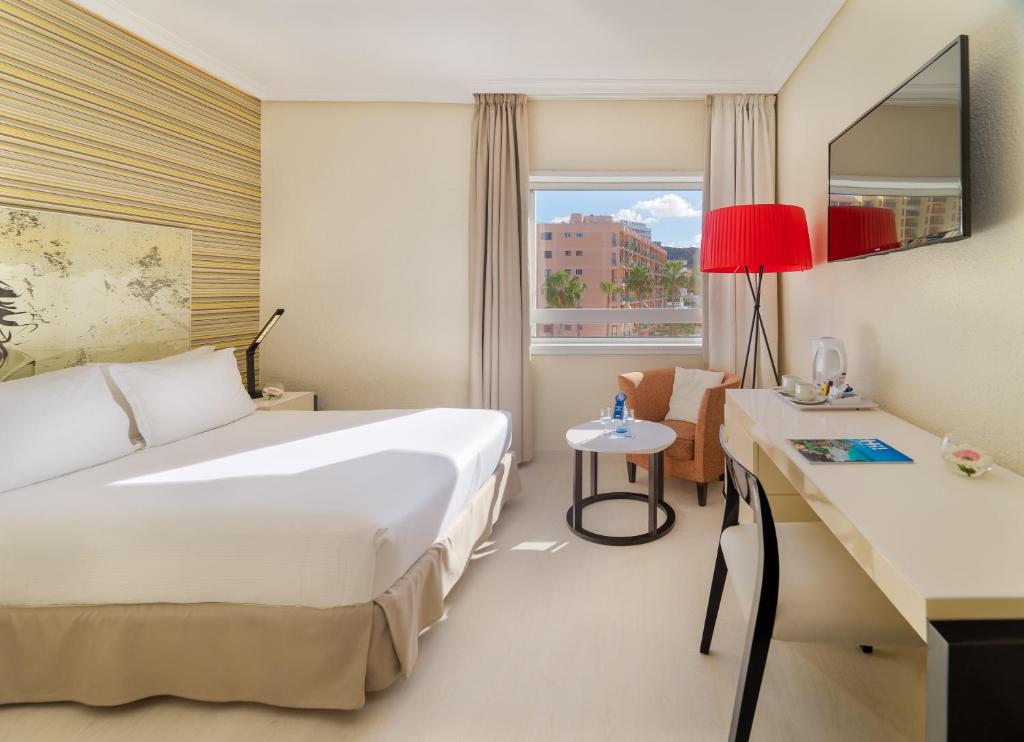 Mūsdienīgs viesnīcas numurs ar vienu gultu, rakstāmgaldu un ērtu atpūtas stūri. Logā redzama pilsētas ainava ar palmām un sauli.