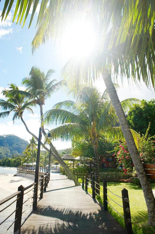 Tropu promenāde ar palmām un saules gaismu, kas iznāk cauri kokiem, radot mierīgu pludmales atmosfēru. Ideāla vieta relaksācijai un atpūtai.
