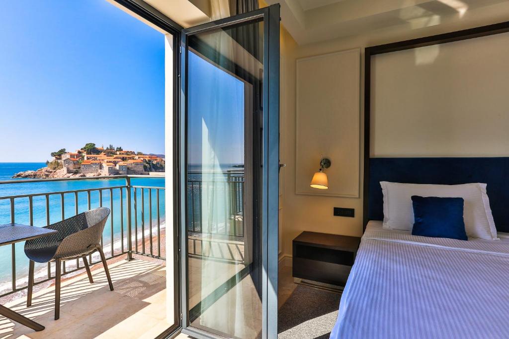 Mūsdienīga viesnīcas istaba ar balkonu, no kura paveras skats uz jūru un piekrastes ciematu. Gaismas un komforta apvienojums nodrošina relaksējošu atmosfēru.