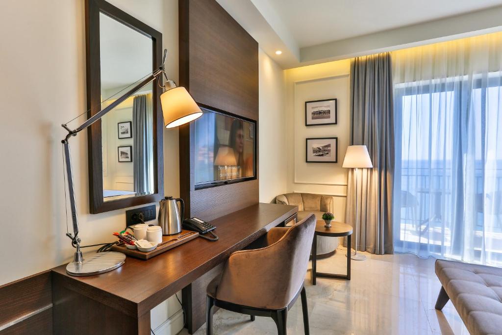 Moderns viesnīcas numurs ar rakstāmgaldu, spoguli un ērtām mēbelēm, kas nodrošina komfortablu atpūtu. Logi ar caurspīdīgām aizkariem piedāvā skatu uz ārpusi.