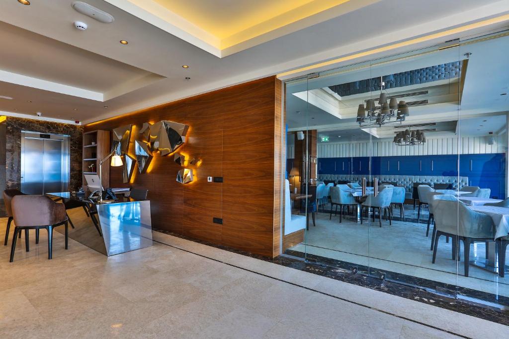 Mūsdienīgs restorāna interjers ar elegantām mēbelēm un stikla durvīm, kas vada uz ēdamzonu. Apsildāmā apgaismojuma un mākslas akcentu kombinācija rada viesmīlīgu atmosfēru.