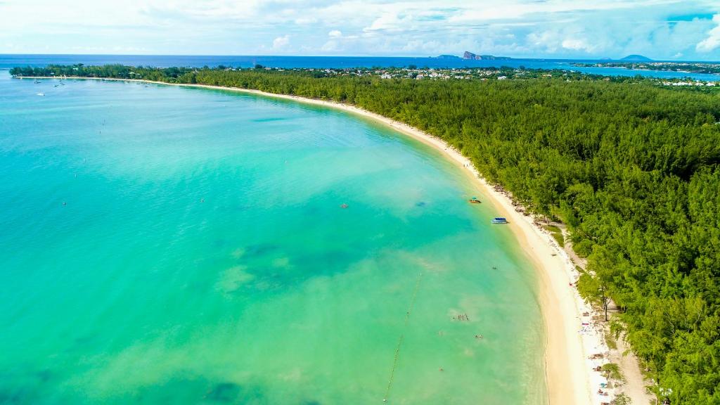 Skaista pludmale ar zilganiem ūdeņiem un zaļām kokiem, kas stiepjas gar piekrasti. Ideāla vieta relaksācijai un ūdens aktivitātēm.