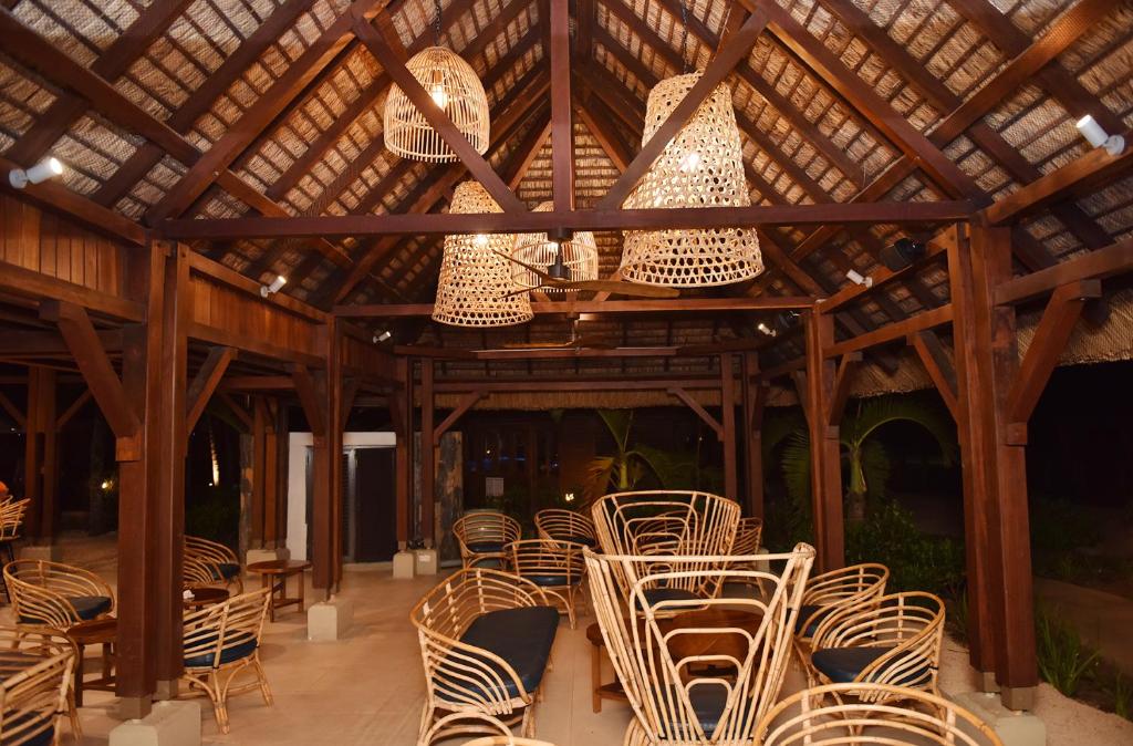 Koka konstrukcijas restorāna interjers ar dabiskām rotājumām un elegantiem, vītinātiem gaismas ķermeņiem, radot siltu un viesmīlīgu atmosfēru.