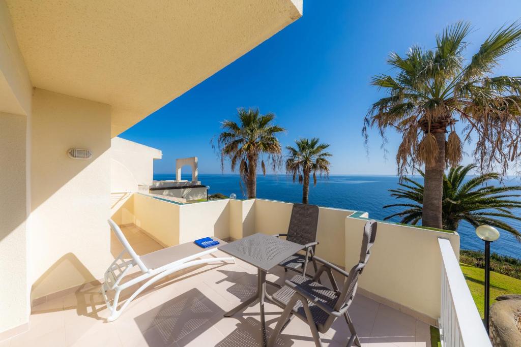 Terase ar skatu uz jūru, kurā redzami palmu koki un mēbeļu komplekts atpūtai. Ideāla vieta relaksācijai un saulainām dienām.