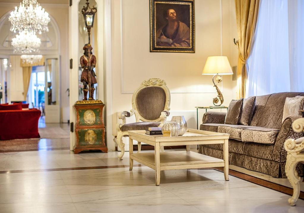 Eleganta viesnīcas iekšējā telpa ar grezniem dīvāniem, stilīgu apgaismojumu un mākslas darbiem pie sienām. Telpa ir izsmalcināta un aicinoša, radot patīkamu atmosfēru.