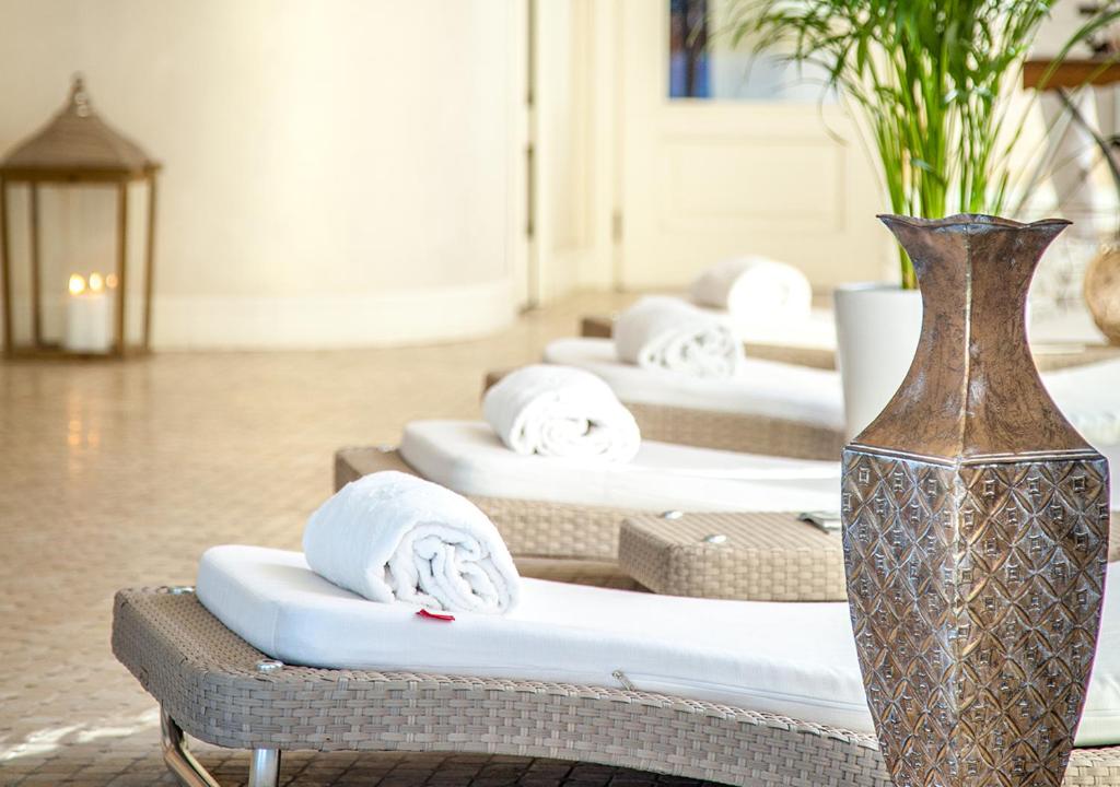 Skaista un relaksējoša spa vide ar atpūtas krēsliem, uz kuriem novietoti balti dvieļi, un dekoratīvā vāze, kas papildina atmosfēru.