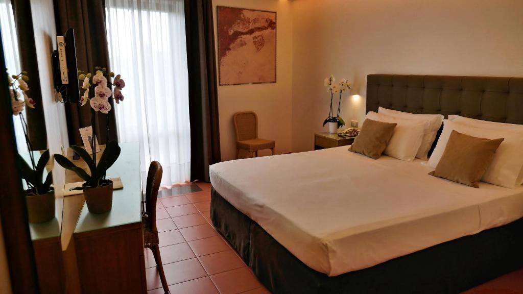 Elegants numurs Rada Siri Hotel ar lielu gultu un orhidejām.