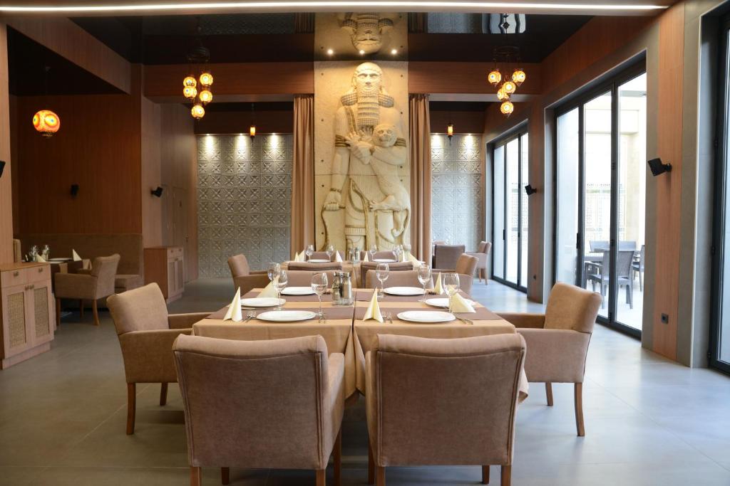 Mūsdienīgs restorāns ar elegantiem galdiem un krēsliem, kurā izceļas liela akmens statuja. Interjers ir gaišs un stilīgs, ar plašiem logiem, kas ļauj ieplūst dabiskajai gaismai.