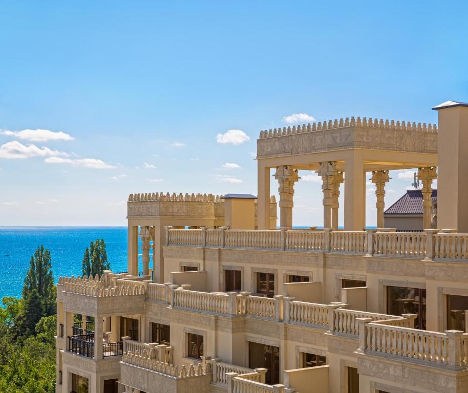 Jūras krastā esoša luksusa viesnīca ar arhitektoniski elegantām terasēm un skatu uz zilo jūru. Mājīgā atmosfēra ar saulainām debesīm un zaļiem kokiem.